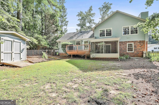 back of property featuring a storage shed, a sunroom, fence, a yard, and brick siding