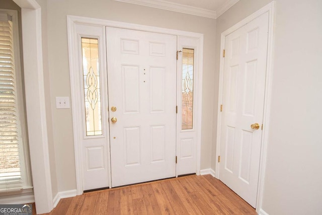 foyer featuring light wood-style flooring, ornamental molding, and baseboards