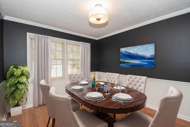 dining area with a textured ceiling, wood finished floors, and crown molding