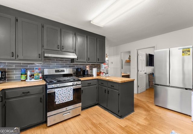 kitchen with stainless steel appliances, light wood-type flooring, under cabinet range hood, and a peninsula