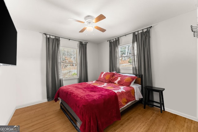 bedroom featuring a ceiling fan, light wood-style flooring, and baseboards