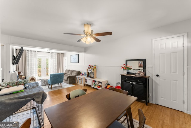 dining room featuring french doors, wainscoting, ceiling fan, and light wood-style flooring