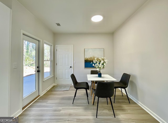 dining area featuring visible vents, light wood-style flooring, and baseboards