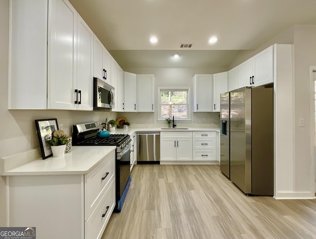 kitchen featuring a sink, visible vents, white cabinets, light countertops, and appliances with stainless steel finishes