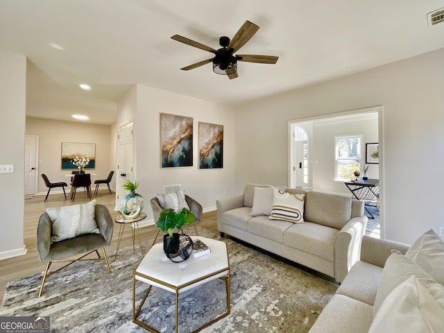 living area with wood finished floors, visible vents, and baseboards