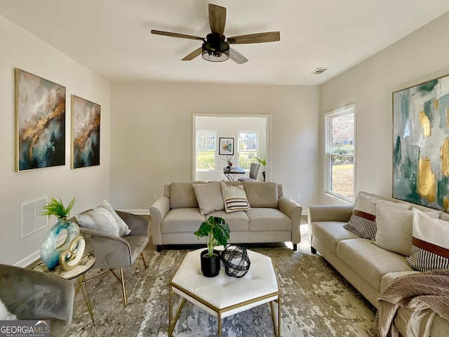 living room featuring a ceiling fan, visible vents, and baseboards