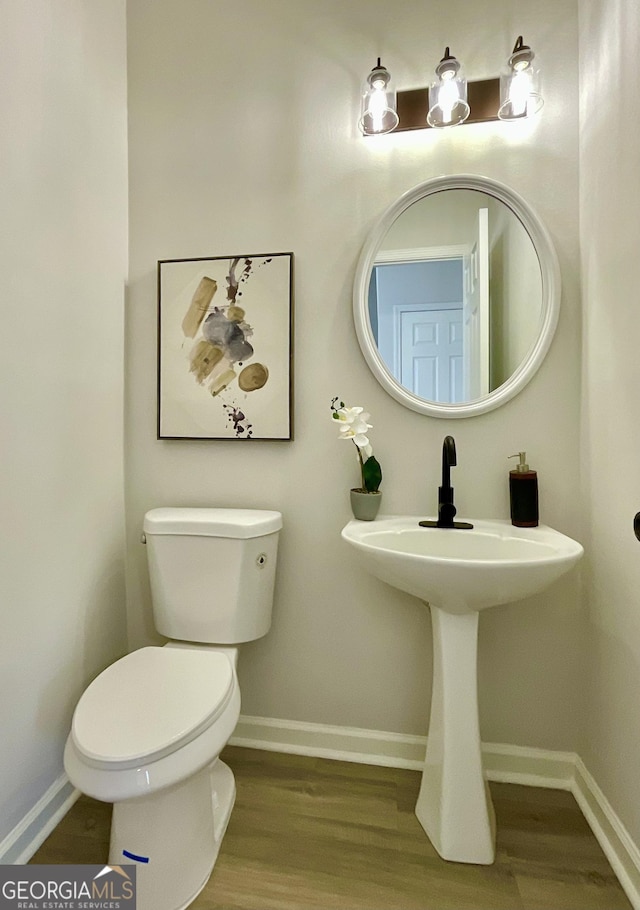 half bathroom featuring toilet, baseboards, and wood finished floors