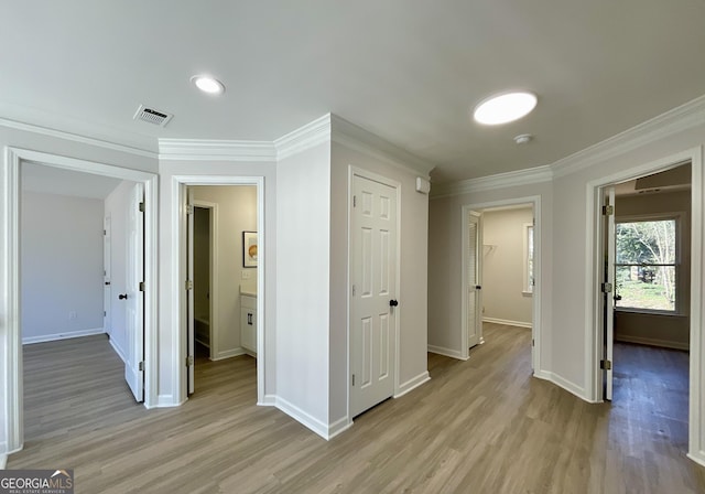 hallway with ornamental molding, light wood-type flooring, and visible vents