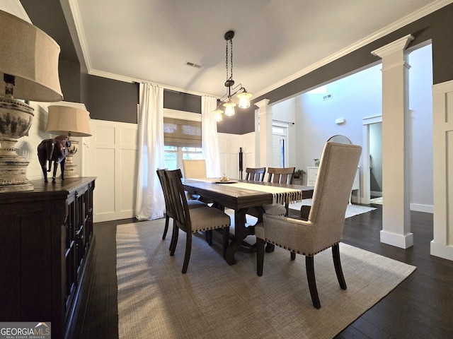 dining space featuring ornamental molding, a decorative wall, and ornate columns