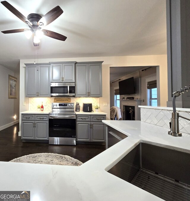 kitchen featuring appliances with stainless steel finishes, light countertops, a sink, and gray cabinetry