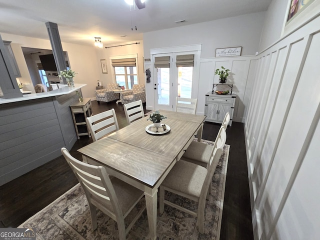 dining area with a wainscoted wall, visible vents, a decorative wall, and dark wood-type flooring