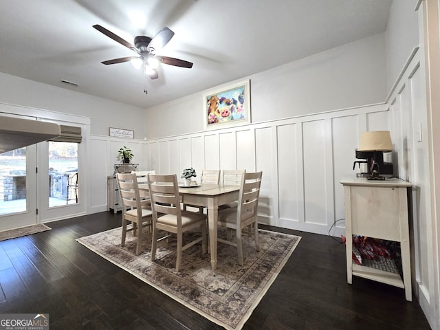 dining room featuring a decorative wall, dark wood-type flooring, and wainscoting