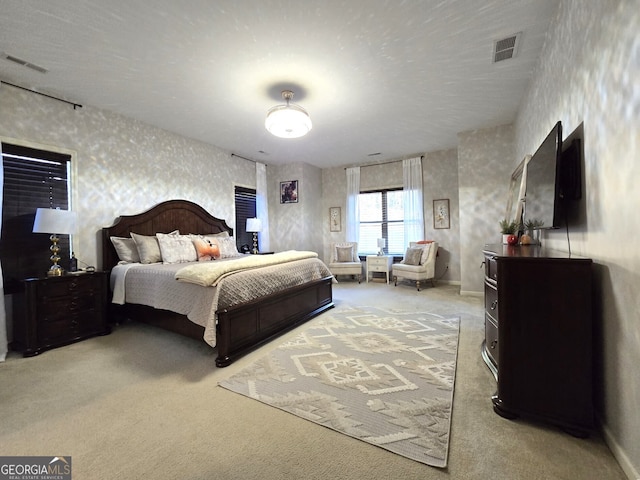 bedroom featuring carpet floors, visible vents, baseboards, and wallpapered walls