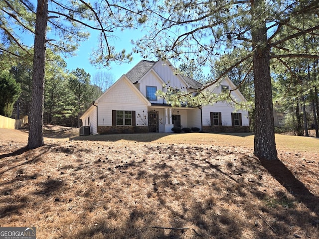 modern inspired farmhouse featuring board and batten siding, stone siding, and central air condition unit