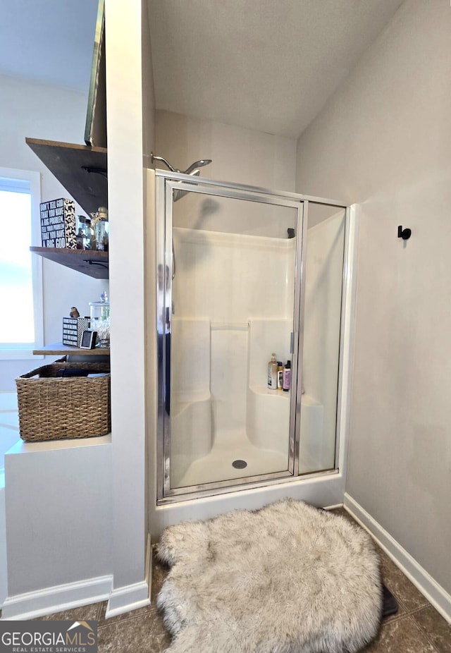 full bath featuring a shower stall and baseboards