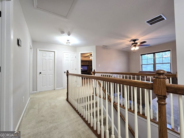 corridor with light colored carpet, baseboards, visible vents, and an upstairs landing