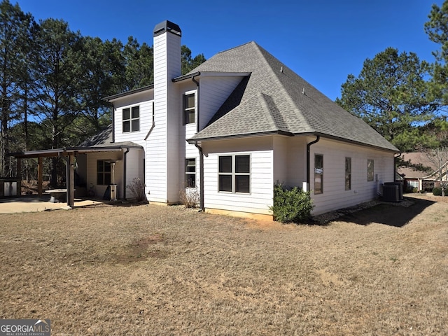 back of property featuring a patio area, roof with shingles, a chimney, and central air condition unit