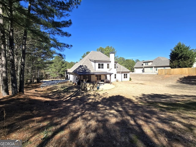 back of house featuring a patio area, a chimney, and fence