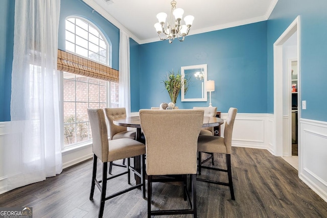 dining area with crown molding, a wainscoted wall, a notable chandelier, and dark wood finished floors