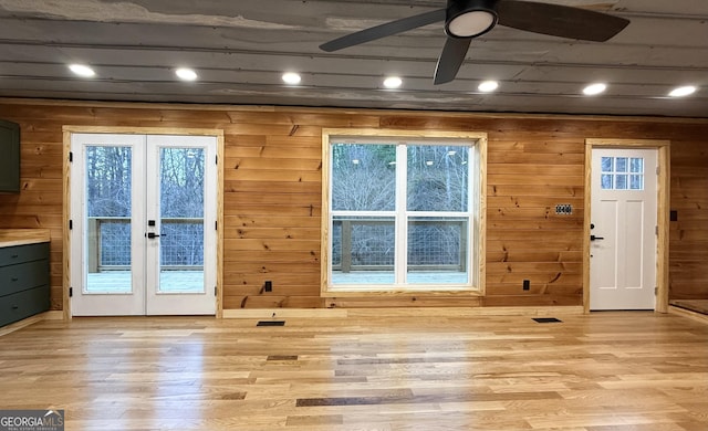 doorway to outside with a ceiling fan, french doors, wooden walls, and light wood finished floors