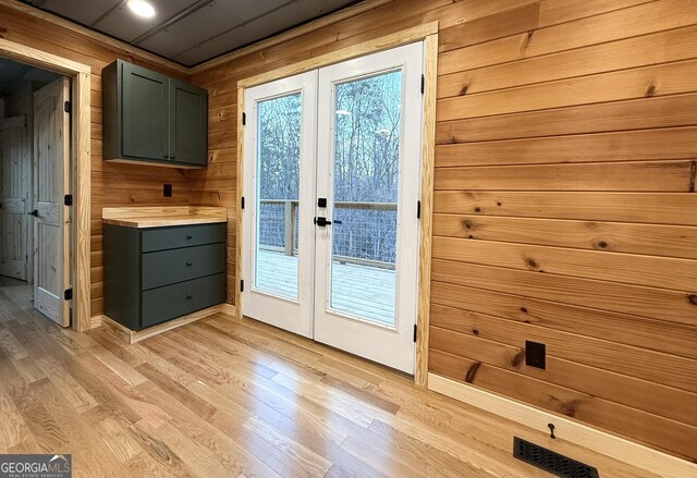 doorway to outside with visible vents, french doors, light wood-style flooring, and wooden walls