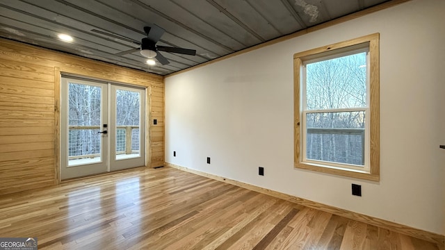 interior space with light wood-style flooring, baseboards, a ceiling fan, and french doors