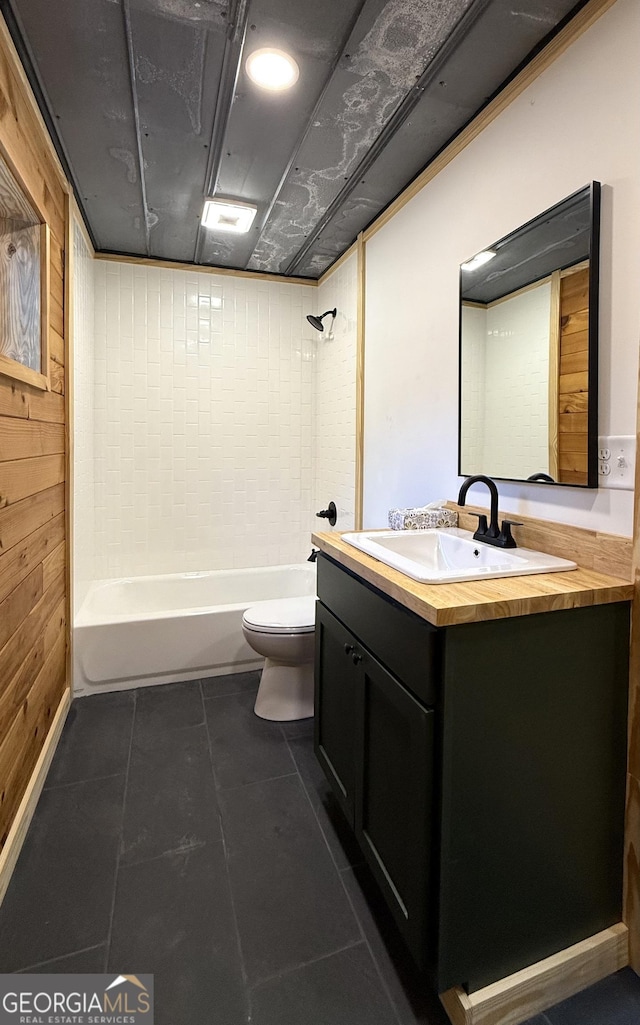 full bathroom featuring shower / washtub combination, toilet, wood walls, vanity, and tile patterned flooring