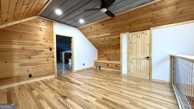 bonus room featuring lofted ceiling, wood walls, light wood-style flooring, and ceiling fan