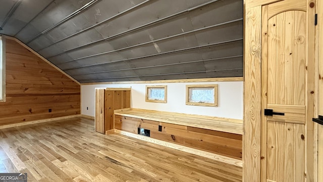 bonus room featuring lofted ceiling, wood walls, baseboards, and wood finished floors