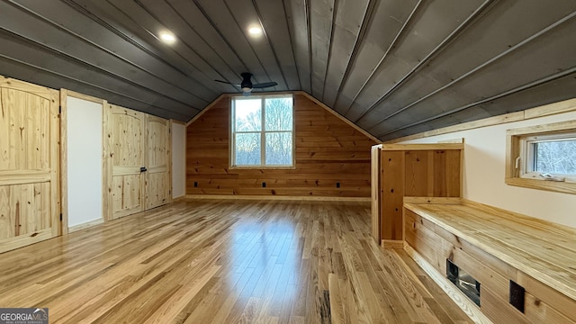 bonus room featuring light wood finished floors, lofted ceiling, ceiling fan, wooden walls, and wooden ceiling