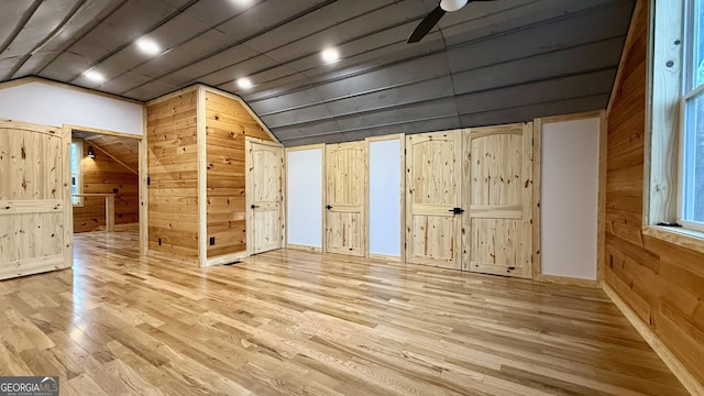 additional living space featuring lofted ceiling, wood walls, and wood finished floors