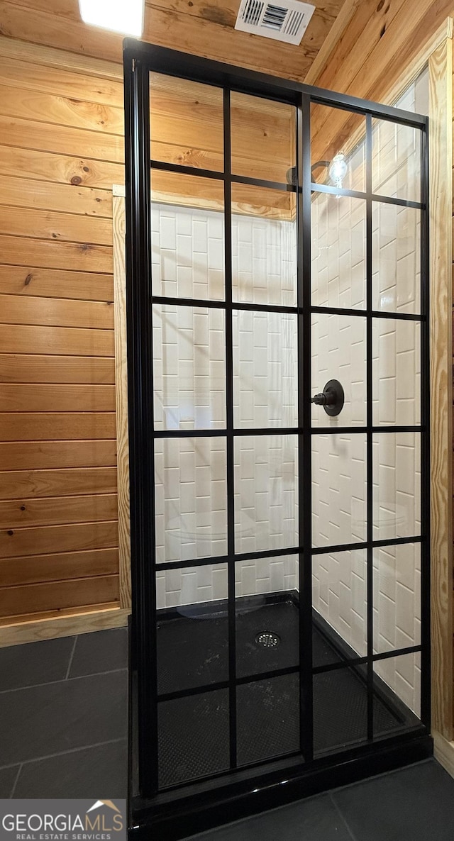 details featuring visible vents, a tile shower, and wooden walls