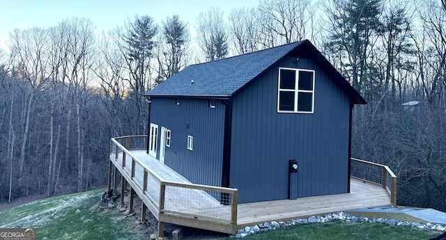 exterior space with a garage, roof with shingles, and a wooden deck