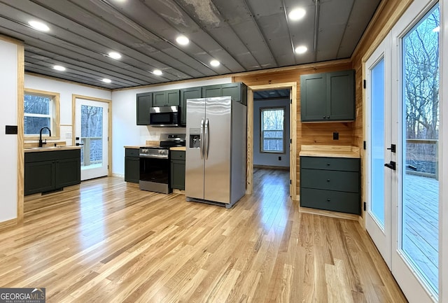 kitchen with a sink, baseboards, light countertops, appliances with stainless steel finishes, and light wood-type flooring