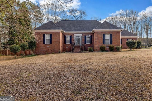 single story home with a shingled roof, brick siding, and fence