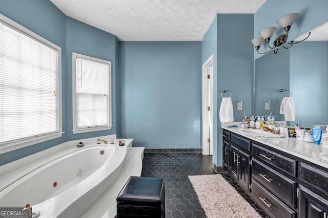 full bathroom with double vanity, a sink, a textured ceiling, a jetted tub, and baseboards