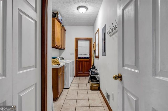 laundry area featuring light tile patterned floors, visible vents, cabinet space, a textured ceiling, and electric panel