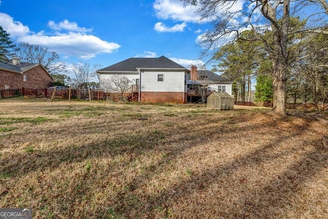 rear view of house with a yard, a greenhouse, fence, and an outdoor structure