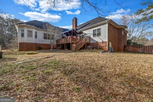 rear view of house featuring brick siding, a chimney, fence, a wooden deck, and stairs