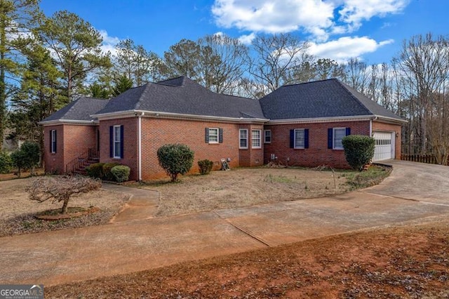 view of front facade with driveway, brick siding, and an attached garage