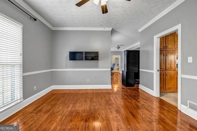 unfurnished living room featuring a textured ceiling, crown molding, and wood finished floors