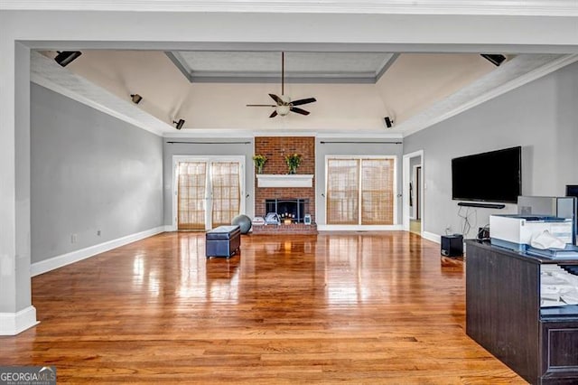 living area featuring baseboards, a healthy amount of sunlight, a fireplace, and light wood finished floors