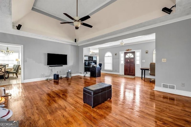 living room with a raised ceiling, wood finished floors, visible vents, and baseboards