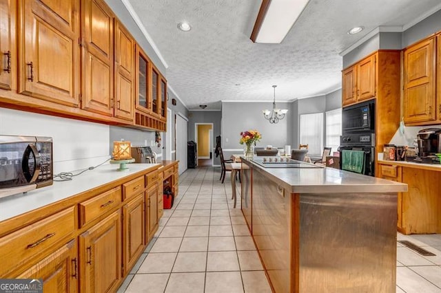 kitchen with a center island, a notable chandelier, brown cabinetry, light tile patterned flooring, and black appliances