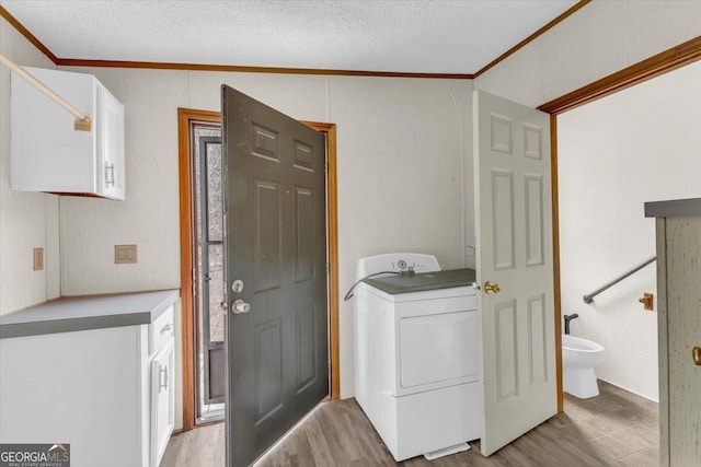 laundry room with ornamental molding, washer / clothes dryer, cabinet space, and light wood-style floors