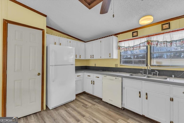 kitchen featuring white appliances, a sink, white cabinets, vaulted ceiling, and dark countertops