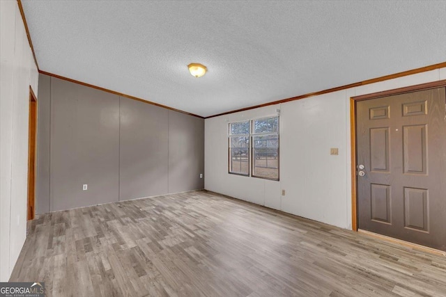 interior space featuring light wood-style flooring, ornamental molding, and a textured ceiling