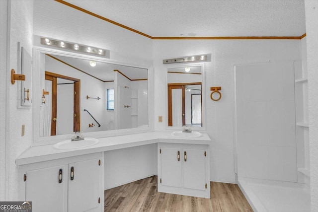 full bathroom featuring crown molding, a sink, a textured ceiling, and wood finished floors