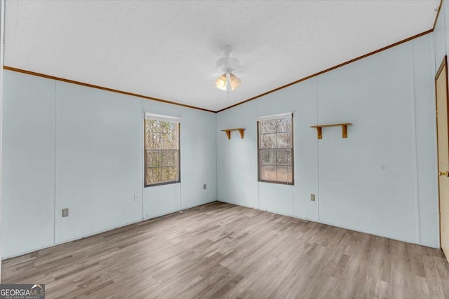 unfurnished room featuring light wood-style flooring, a textured ceiling, ceiling fan, and crown molding