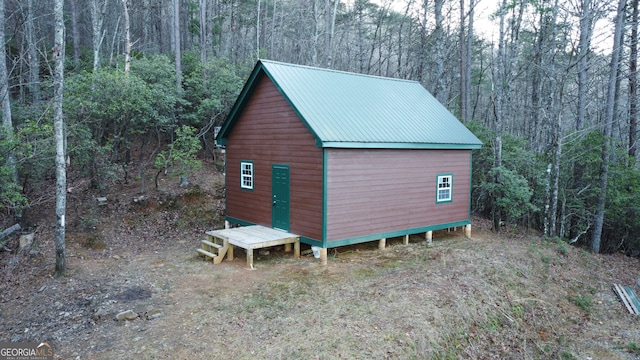 view of outdoor structure with a forest view and an outbuilding